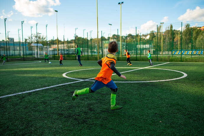 Boy playing soccer field school football stadium green grass background